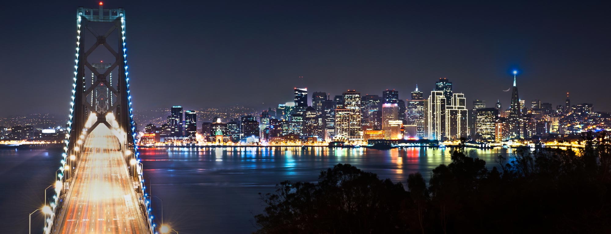 Photo of a bridge leading to a city at night