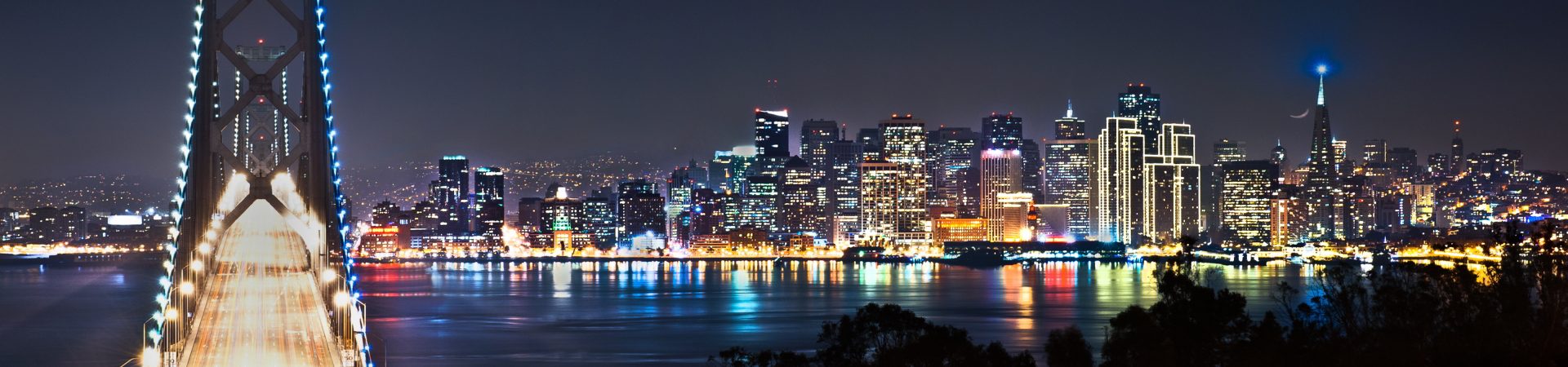 Photo of a bridge leading to a city at night